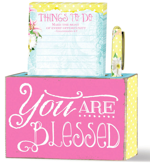 This blox giftset from our Sunshine Daisies collection features a wood blox, notepad and pen. Brightly colored tabletop decor to lift your spirit. Inspirational message of "you are blessed."